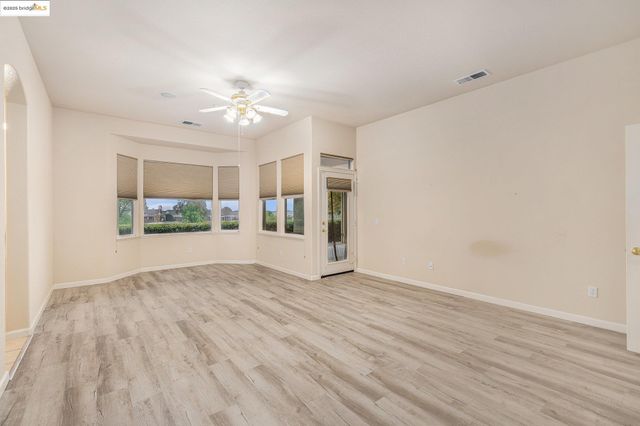 a view of an empty room with a window and a ceiling fan