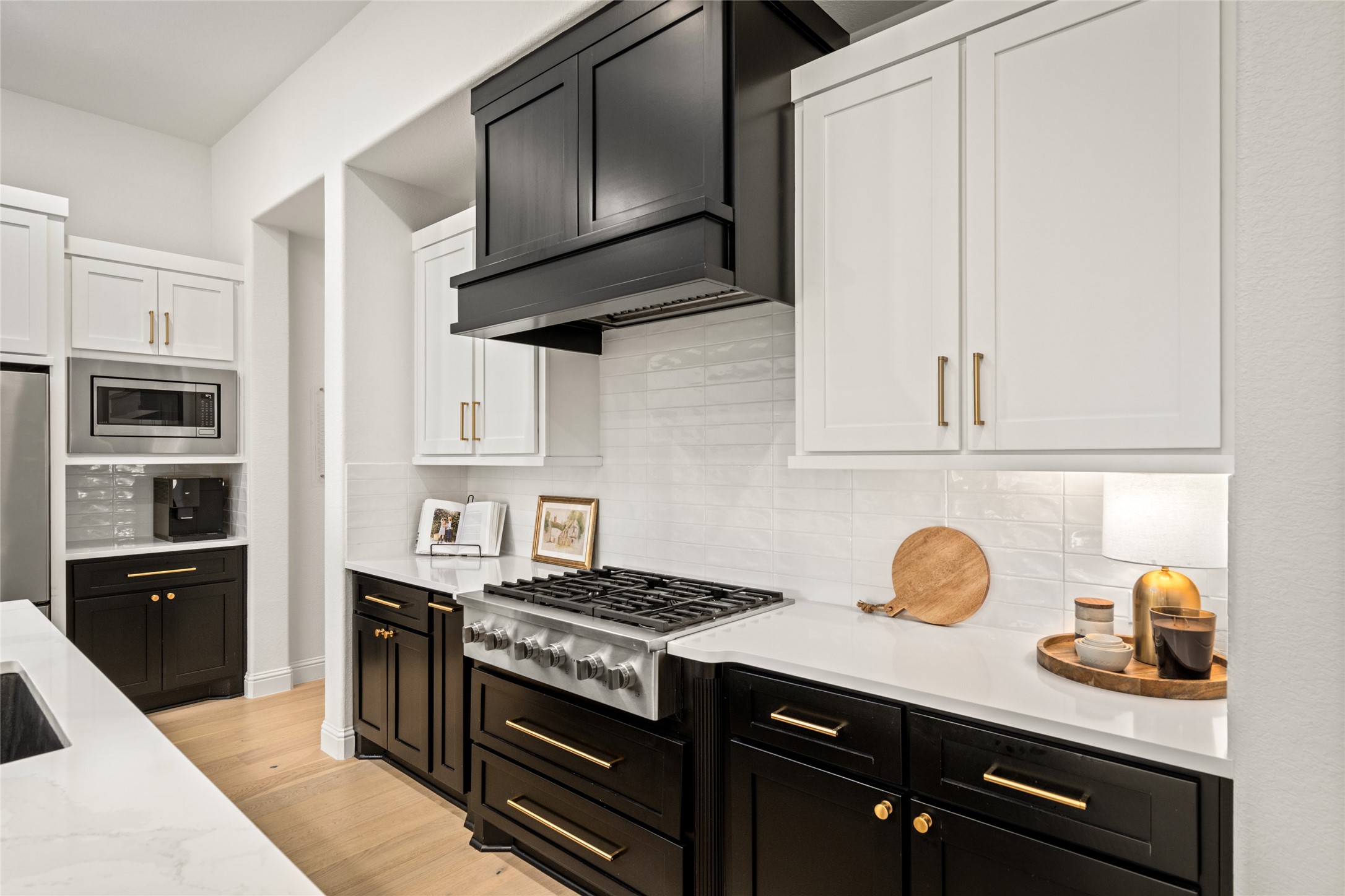 17461 Bayflower Conroe, TX 77385 - Photo 11 of 49 Striking two-tone cabinetry and a professional-grade gas range. Sleek quartz countertops and tile backsplash are complemented by modern gold hardware.