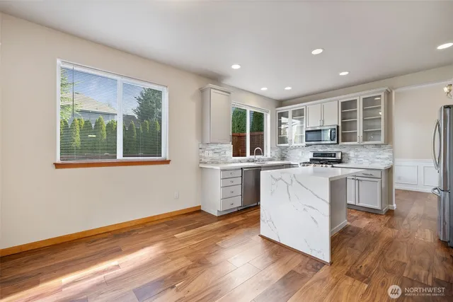 a kitchen with white cabinets and wooden floor