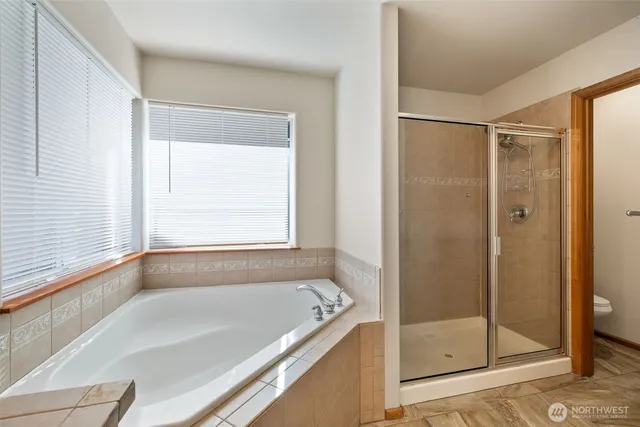 a bathroom with a granite countertop tub double vanity sink and a large mirror