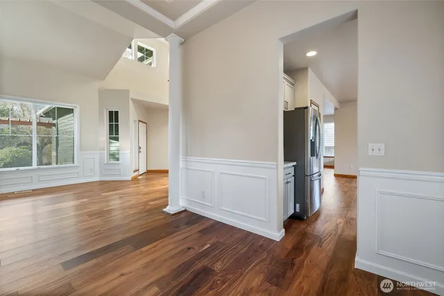 an empty room with wooden floor and entrance to ceiling window