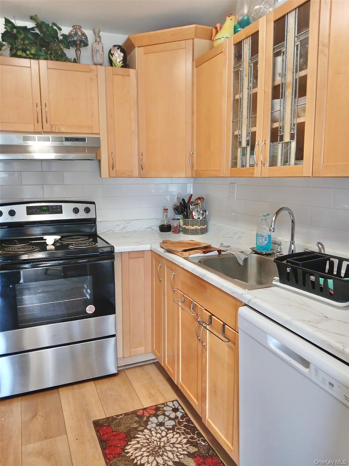 427 Aylesbury Court, Unit A Ridge, NY 11961 - Photo 3 of 16 a kitchen with stainless steel appliances a stove a sink and a microwave