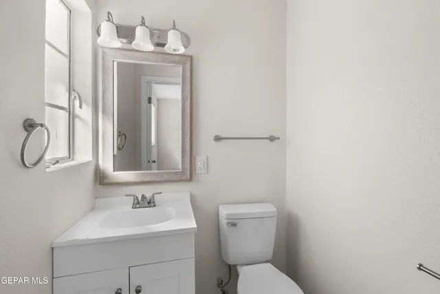 a bathroom with a toilet sink vanity and mirror