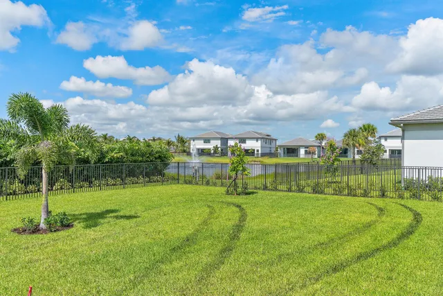 a view of swimming pool with a yard and palm trees