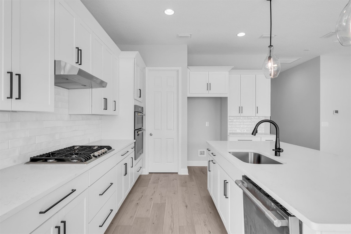 454 Slash Pine Place Yulee, FL 32097 - Photo 14 of 34 a kitchen with stainless steel appliances a sink dishwasher a stove and white cabinets with wooden floor