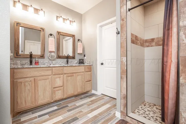 a spacious bathroom with a granite countertop sink a mirror and a shower