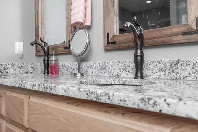 a bathroom with a granite countertop sink and a mirror