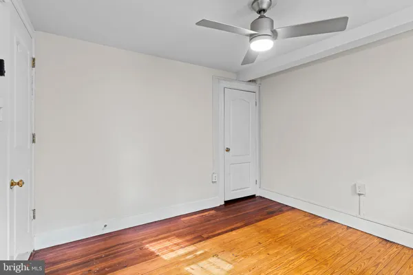 a view of empty room with wooden floor and ceiling fan