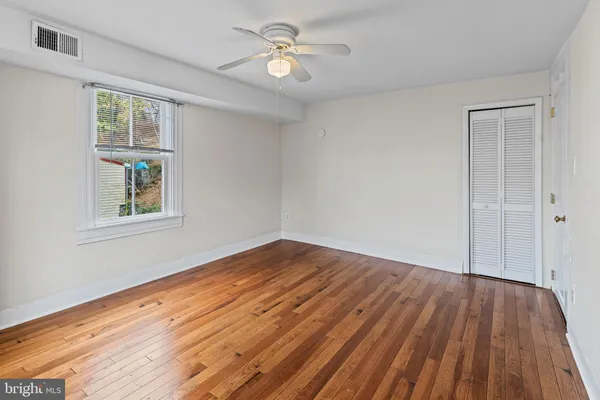 a view of empty room with wooden floor and fan