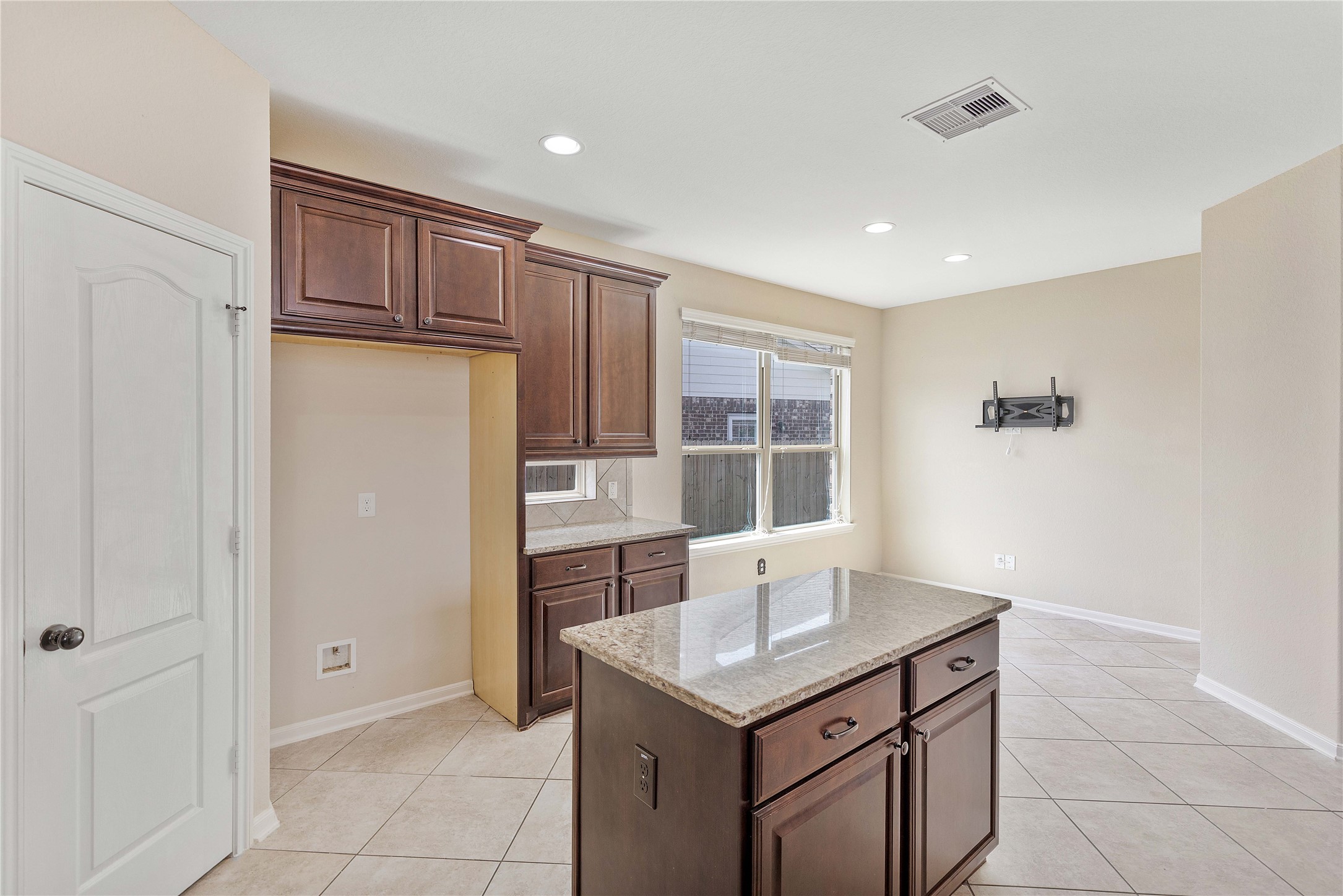 17206 Upper Ridge Lane Humble, TX 77346 - Photo 8 of 50 Bright kitchen with granite countertops, a central island, and rich wooden cabinets. Tile flooring and ample natural light from a large window create an inviting atmosphere.