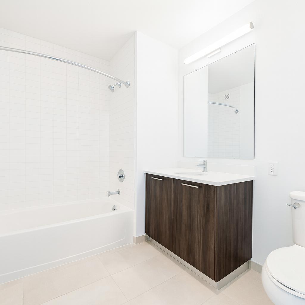 1524 Sheepshead Bay Road, Unit 17D Brooklyn, NY 11235 - Photo 6 of 24 a bathroom with a sink a toilet and shower