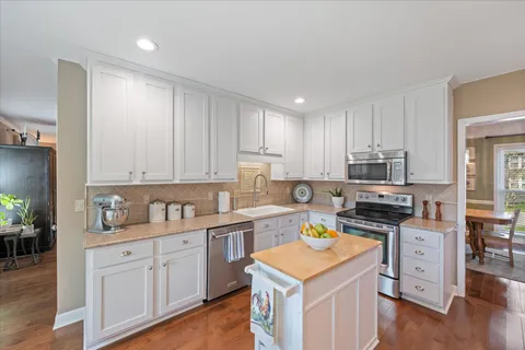 a kitchen with cabinets appliances wooden floor and a window