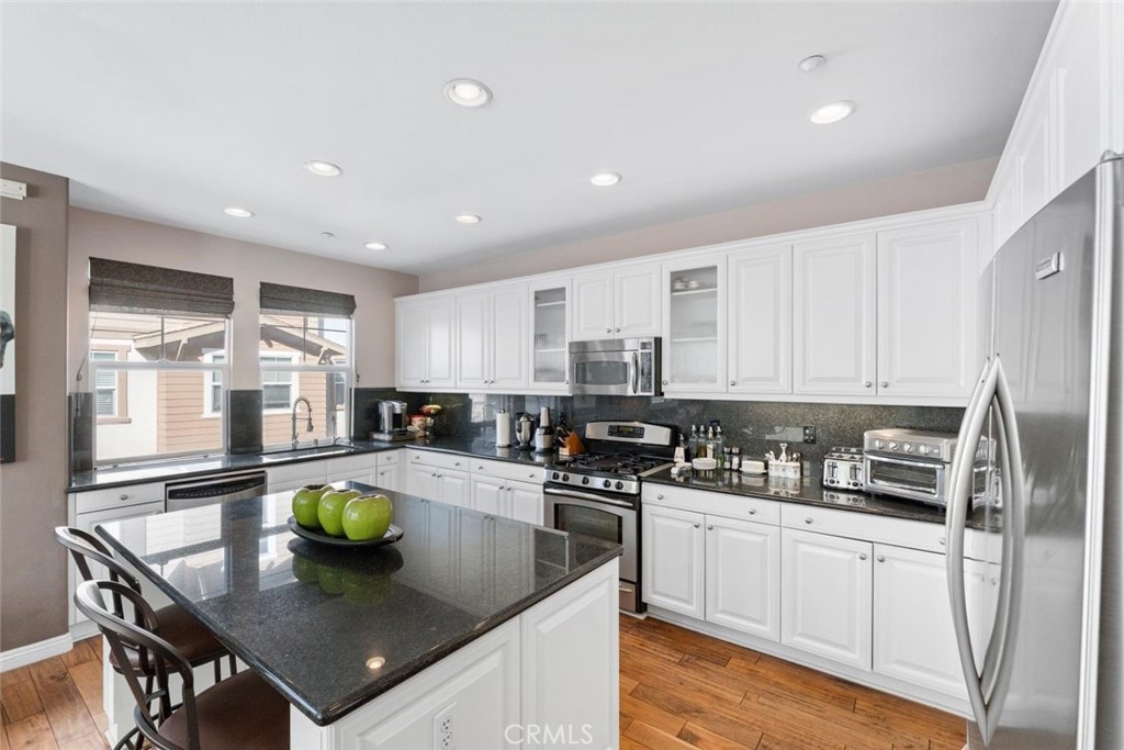 22 Arlington Street Ladera Ranch, CA 92694 - Photo 12 of 51 a kitchen with a sink a stove and chairs with wooden floor