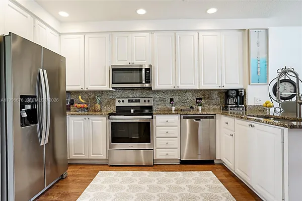 a kitchen with granite countertop a refrigerator stove and microwave