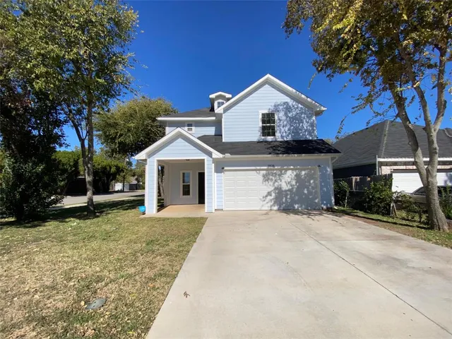 a view of a house with a yard and large tree