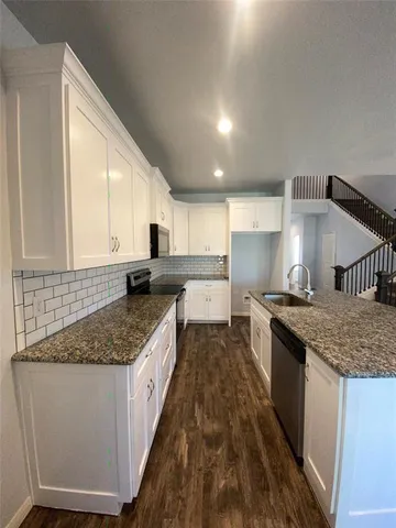 a large kitchen with granite countertop a sink and a stove