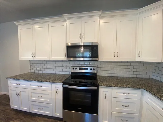 a kitchen with white cabinets and appliances