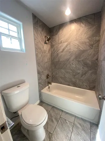 a bath tub sitting next to a white toilet and a shower