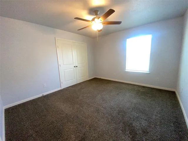 a view of an empty room and chandelier fan