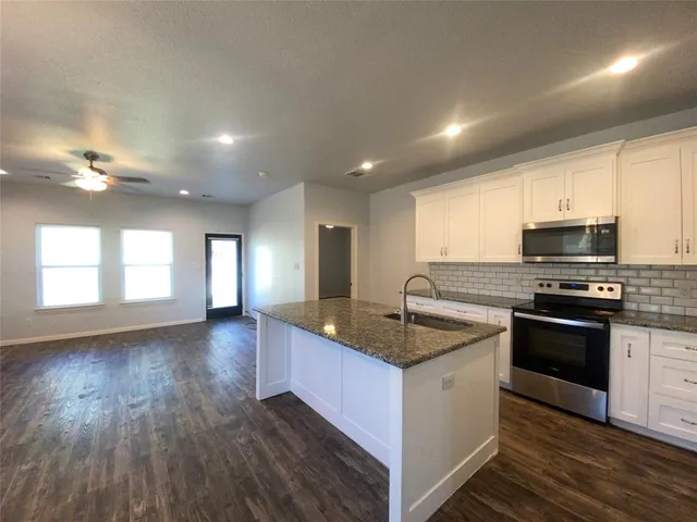 a kitchen with stainless steel appliances granite countertop a sink stove and cabinets