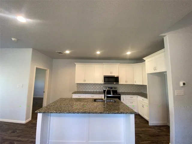 a kitchen with stainless steel appliances granite countertop a sink a stove and a refrigerator