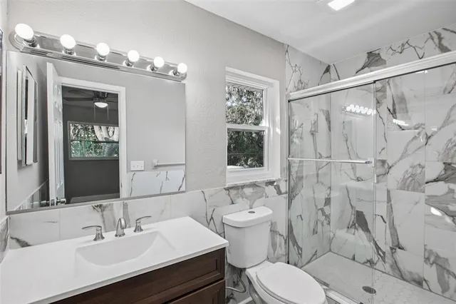 a bathroom with a sink toilet a mirror and shower