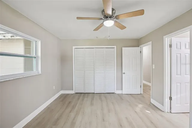 an empty room with windows and fan