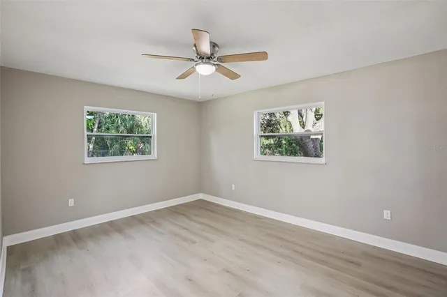 a view of an empty room with wooden floor and a window