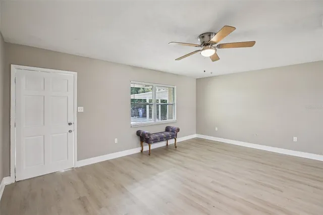 a view of an empty room with a window and wooden floor