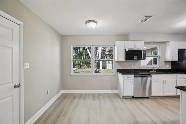 a kitchen with granite countertop white cabinets and white appliances
