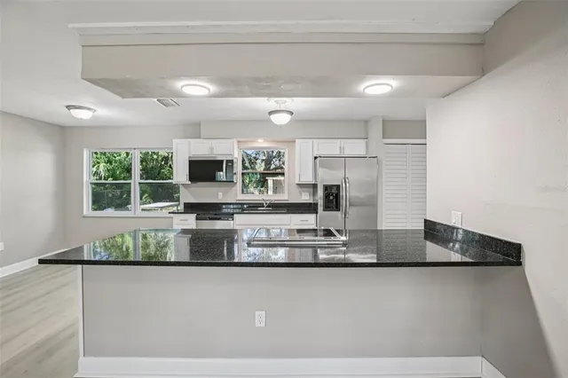 a view of a kitchen with stainless steel appliances granite countertop a refrigerator a stove and a sink