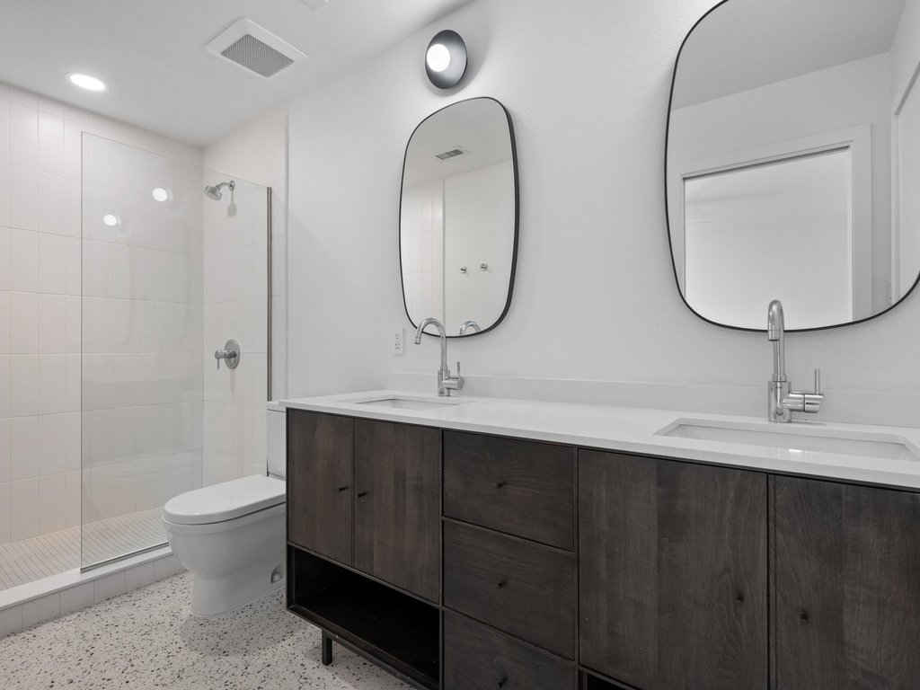6902 Meadow Run Austin, TX 78745 - Photo 15 of 33 Full bathroom featuring double vanity, a shower stall, and dark aggregate flooring
