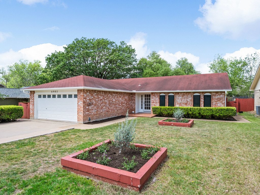 6902 Meadow Run Austin, TX 78745 - Photo 33 of 33 Ranch-style house featuring an attached garage, a garden, driveway, and brick siding