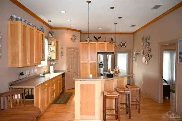 a kitchen with stainless steel appliances kitchen island granite countertop a refrigerator a sink a stove and a dining table with wooden floor