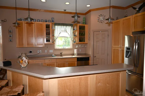 a kitchen with stainless steel appliances kitchen island granite countertop a refrigerator a stove and a sink with wooden floor