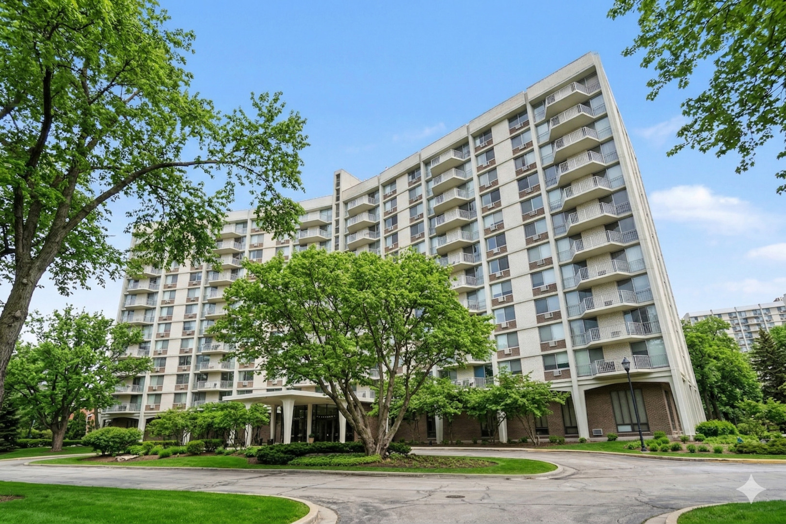 a view of a tall building next to a big yard and large trees