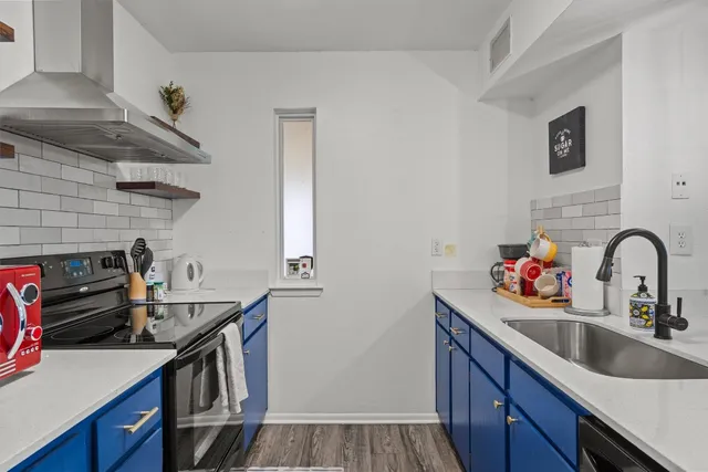 a kitchen with stainless steel appliances a sink dishwasher a stove a microwave oven and a dining table with wooden floor