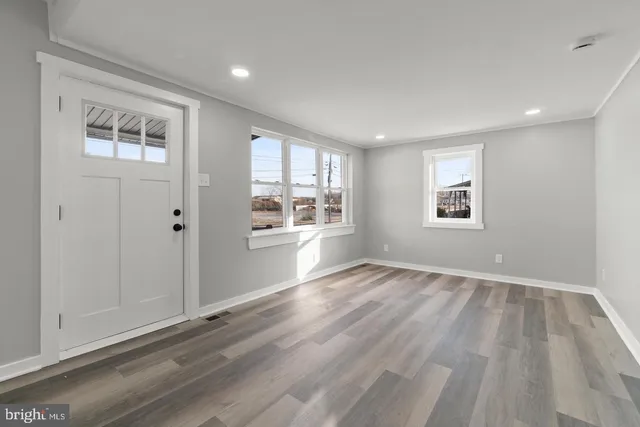 a view of an empty room with a window and wooden floor