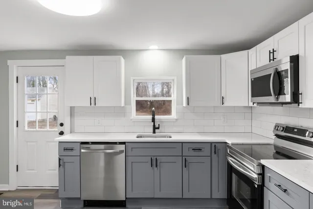 a kitchen with stainless steel appliances granite countertop a sink dishwasher a stove and a microwave oven with cabinets