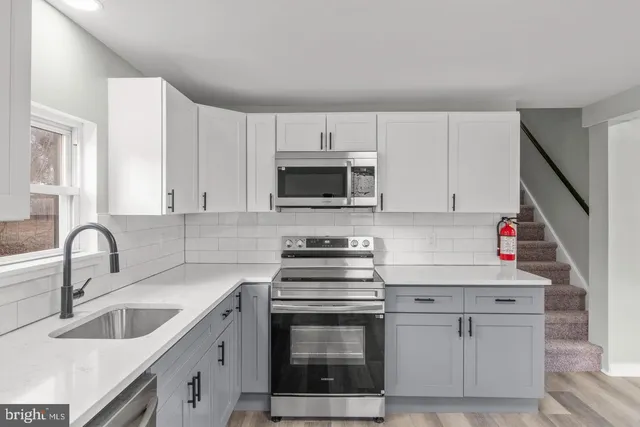 a kitchen with white cabinets appliances and sink