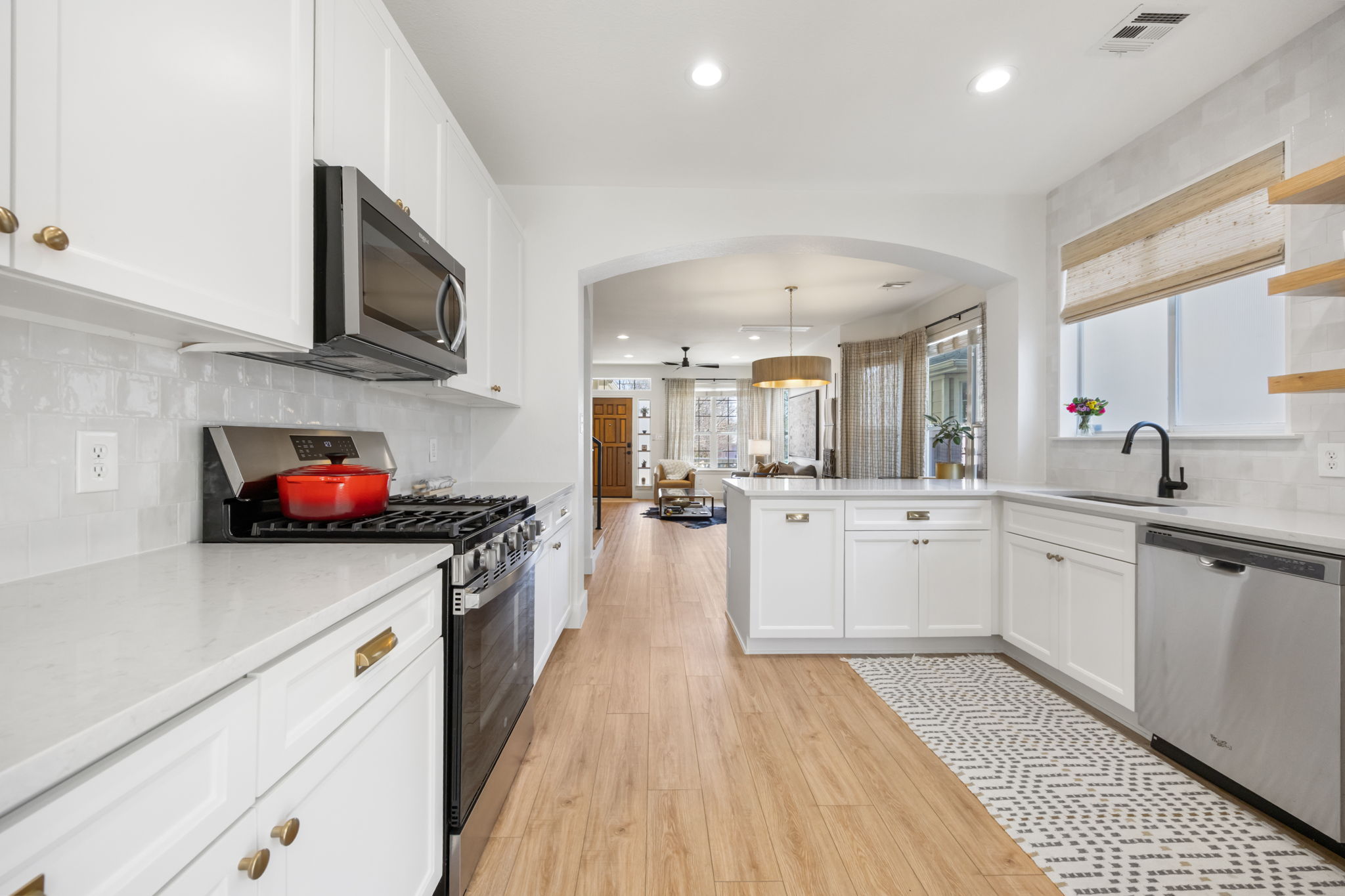 2510 Thornton Road Austin, TX 78704 - Photo 10 of 40 a kitchen with stainless steel appliances a sink dishwasher stove refrigerator and white cabinets with wooden floor