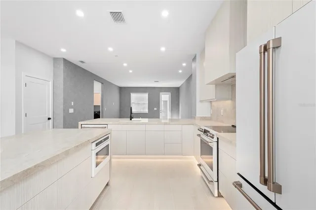 a large white kitchen with a stove a sink and a refrigerator