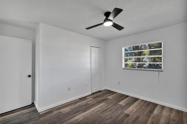 a view of empty room with wooden floor and fan