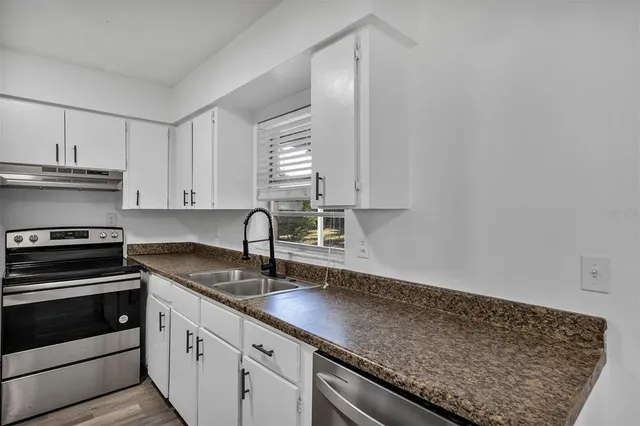 a kitchen with granite countertop a sink stove and cabinets