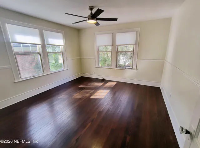 a view of an empty room with wooden floor and a window