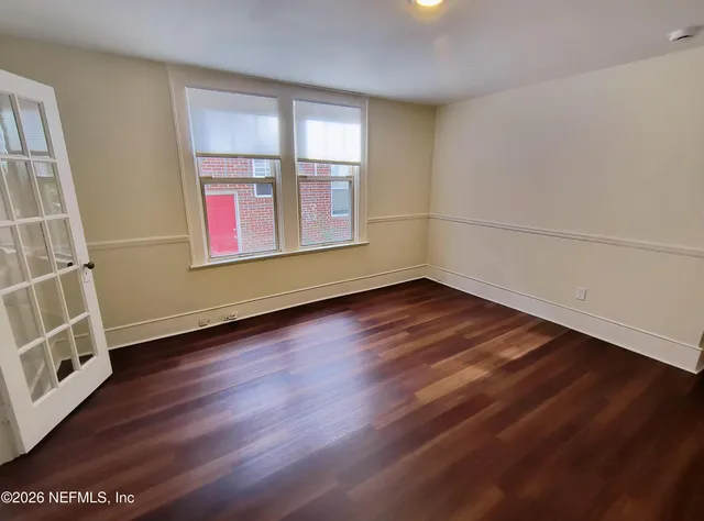 an empty room with wooden floor and windows