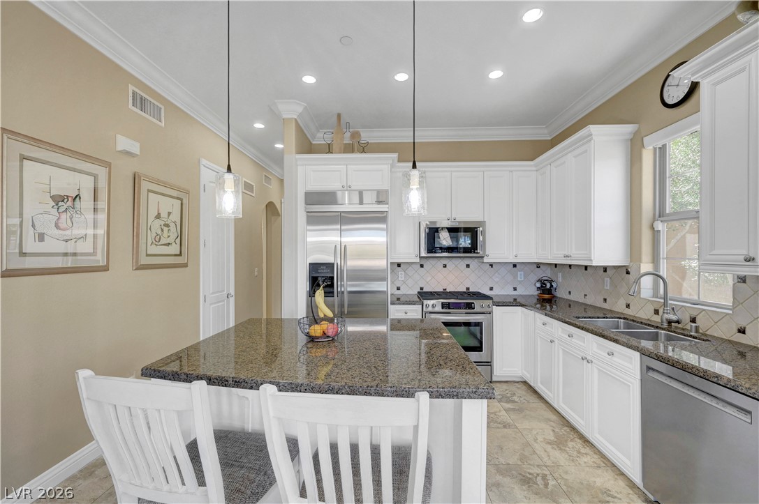 10 Strada Bella Vista, Unit 101 Henderson, NV 89011 - Photo 20 of 64 Kitchen with stainless steel appliances, a breakfast bar, white cabinets.