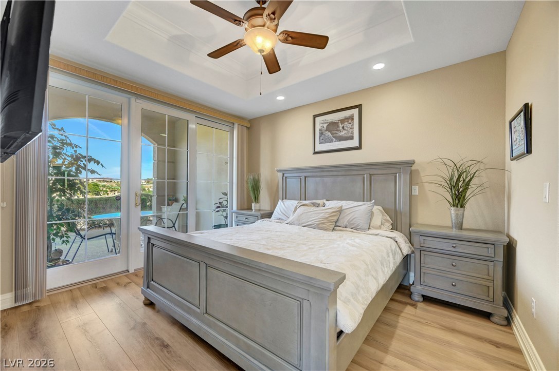 10 Strada Bella Vista, Unit 101 Henderson, NV 89011 - Photo 23 of 64 Bedroom featuring laminate wood finished floors, access to exterior, ceiling fan, recessed lighting, and a raised ceiling