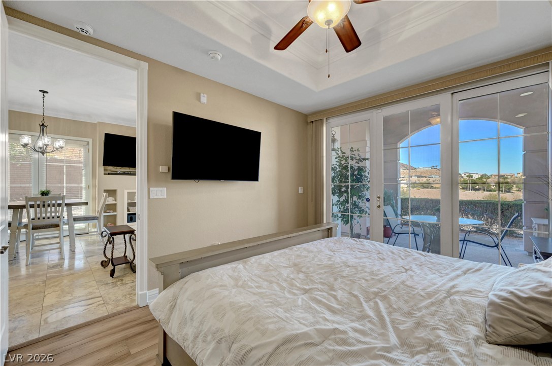 10 Strada Bella Vista, Unit 101 Henderson, NV 89011 - Photo 24 of 64 Bedroom featuring access to exterior, a tray ceiling and crown molding.