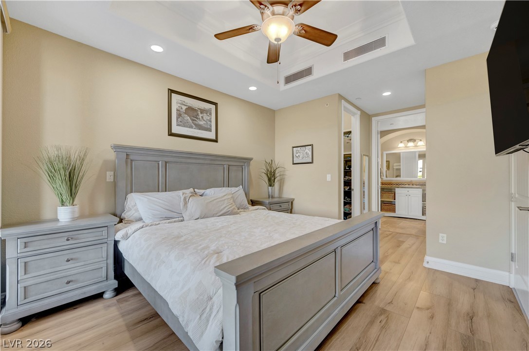 10 Strada Bella Vista, Unit 101 Henderson, NV 89011 - Photo 25 of 64 Bedroom with a walk in closet, laminate wood-style flooring, recessed lighting, ceiling fan, and a raised ceiling